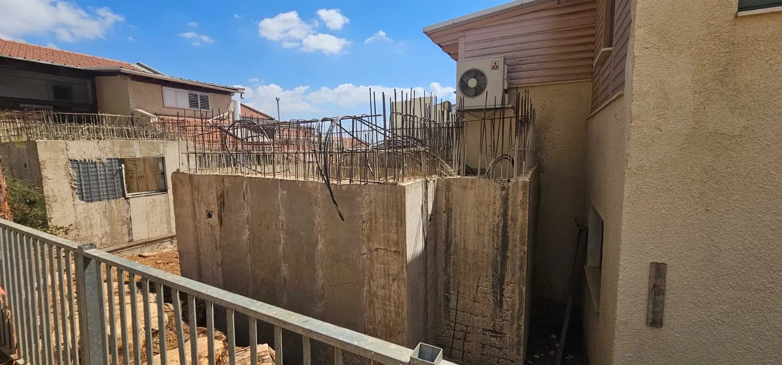 קירות בטון מזוין יצוקים של ממ"ד צמוד לבית פרטי, זיון בולט מלמעלה לקראת יציקת תקרה