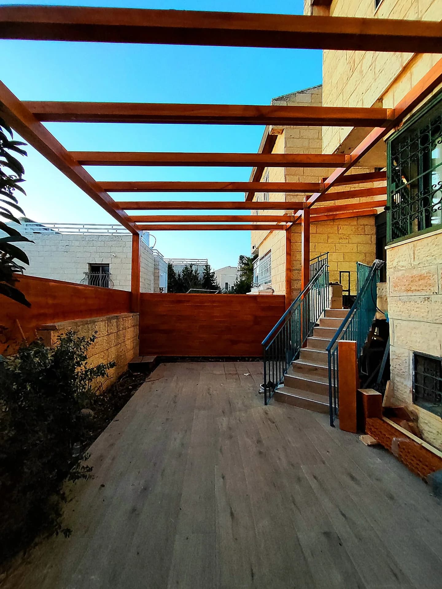 פרגולת עץ בגוון חום עם דק תואם בכניסה לבית פרטי בירושלים, מדרגות אבן