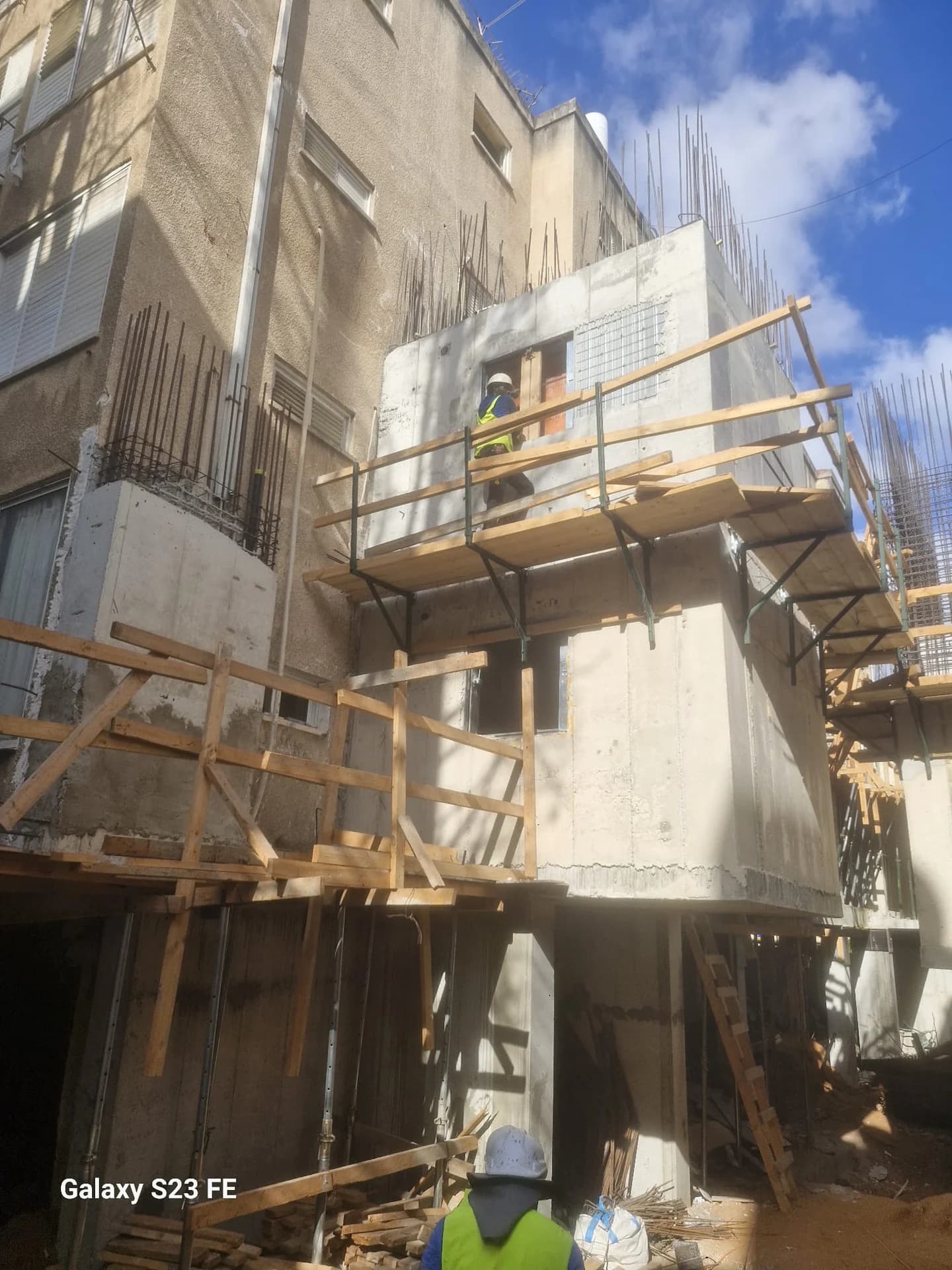 בניית ממ"דים בבניין מגורים משותף, פיגומי עץ, פועלים עם ציוד בטיחות וזיון קירות בולט